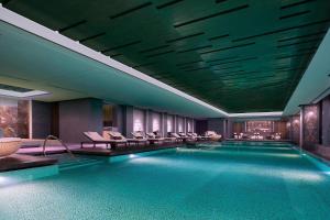 een zwembad in een hotel met stoelen en een zwembad bij Sheraton Qingdao Licang Hotel in Qingdao