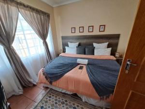 a bedroom with a large bed and a window at Courtlyguesthouse in eMalahleni