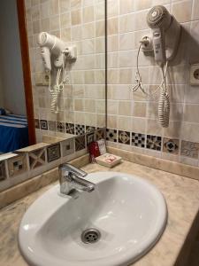 a bathroom sink with two hair dryers and a mirror at Pensión Coral in Barcelona