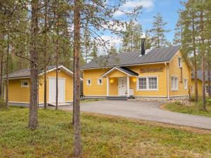a yellow house with a garage in the woods at Holiday Home Jutapirtti by Interhome in Levi