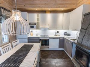 una cocina con armarios blancos y una lámpara de araña en Holiday Home Päivänsäde 8 lapinkulta by Interhome, en Äkäslompolo