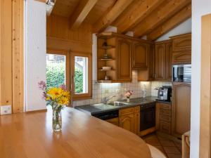 a kitchen with wooden cabinets and a vase of flowers on a table at Holiday Home Midat soleil by Interhome in Verbier