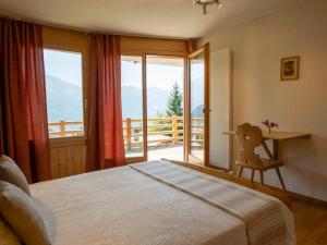 a bedroom with a bed and a desk with a balcony at Holiday Home Midat soleil by Interhome in Verbier