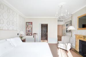 a white bedroom with a bed and a fireplace at Hotel El Palace Barcelona in Barcelona