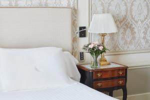 a bedroom with a bed and a table with a lamp and flowers at Hotel El Palace Barcelona in Barcelona