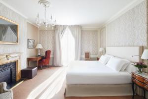 Hotel El Palace Barcelona في برشلونة: غرفة نوم مع سرير أبيض كبير ومدفأة