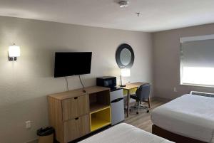 a hotel room with a bed and a desk with a television at Days Inn by Wyndham Dallas Garland West in Garland