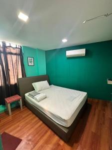 Bett in einem Zimmer mit grüner Wand in der Unterkunft TANGERINE ORIENTAL HOTEL in Kuala Lumpur