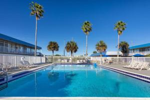 a swimming pool with palm trees in a resort at Days Inn by Wyndham Titusville Kennedy Space Center in Titusville