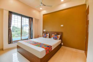 a bedroom with a large bed with a large window at FabHotel Royal Hospitality in Pune