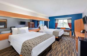 a hotel room with two beds and a television at Microtel Inn and Suites by Wyndham - Cordova in Memphis