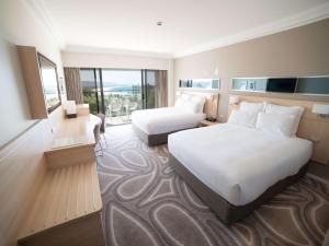 a hotel room with two beds and a large window at Novotel Wollongong Northbeach in Wollongong