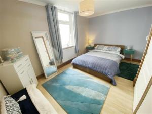 um quarto com uma cama e um grande tapete azul em The Gateway a lovely Spacious Seaside Property close to the beaches , centrally located in Porthcawl em Newton