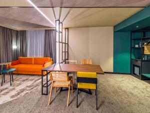 um quarto com uma mesa e cadeiras e um sofá em Novotel Kraków Centrum em Cracóvia