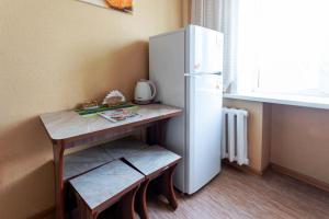 una pequeña cocina con mesa y nevera en Мандарин en Petropavlovsk