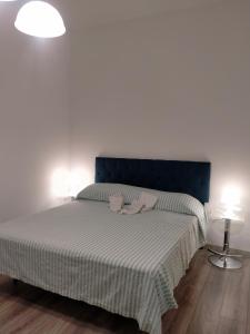 a bedroom with a bed with a blue headboard and two lamps at Setta Apartment in Lido di Ostia