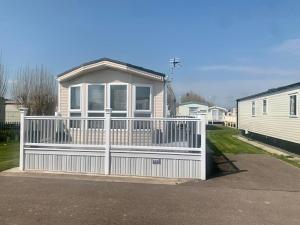 ein weißer Zaun vor einem Haus in der Unterkunft Palm Grove 28 - Golden Palm - Central heating, pet friendly, WiFi, bed linen - Meadow Lakes Caravan & Lodge Hire in Chapel Saint Leonards