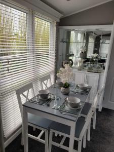 ein Esszimmer mit Tisch und Stühlen und eine Küche in der Unterkunft Palm Grove 28 - Golden Palm - Central heating, pet friendly, WiFi, bed linen - Meadow Lakes Caravan & Lodge Hire in Chapel Saint Leonards