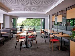a restaurant with wooden tables and chairs and a large window at ibis Hamilton Tainui in Hamilton