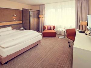 Habitación de hotel con cama grande y escritorio. en Mercure Hotel Dortmund Centrum, en Dortmund