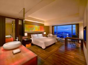 a bedroom with a large bed and a desk and a room at Hyatt Regency Kinabalu in Kota Kinabalu