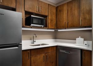 a kitchen with wooden cabinets and a sink and a microwave at Hampton Inn Troy in Troy