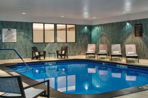 Homewood Suites by Hilton Anchorage في أنكوراج: مسبح في غرفة الفندق مع الكراسي والطاولات