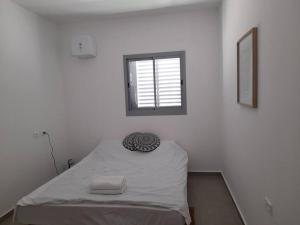 een bed in een witte kamer met een raam bij emily apartment 