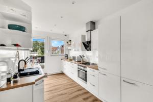 a white kitchen with wooden floors and white cabinets at Altstadt-Refugium Goslar in Goslar