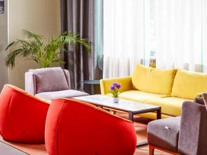 a living room with red and yellow chairs and a table at ibis Styles Makkah in Makkah