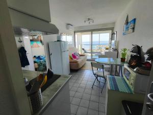 a kitchen and living room with a table and a refrigerator at T2 vue panoramique, piscine, parking, wifi, 2 tv connectées, netflix, clim, ascenseur, salon de jardin teck, barbecue in Sète