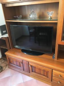 una TV a schermo piatto seduta su un centro di intrattenimento in legno di Sweety Rome House a Roma