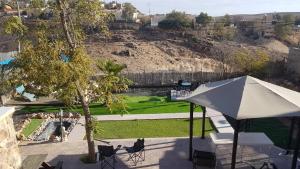 a patio with an umbrella and chairs and a garden at arad rooms & apartments חדרי אירוח ערד in Arad