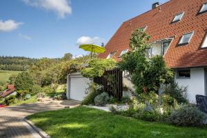 a house with a garage and an umbrella in the yard at Ferienwohnung Panorama in Neusatzeck