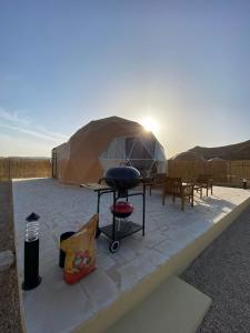 a patio with a grill and a tent at منتجع جلامبنغ - Glamping Resort in Al Fawwāz