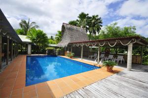 a resort swimming pool with a thatched roof at Kosrae Nautilus Resort in Yepan
