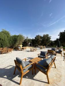 eine Gruppe von Stühlen und Tischen auf einer Terrasse in der Unterkunft منتجع جلامبنغ - Glamping Resort in Al Fawwāz