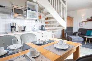 a kitchen and dining room with a table and chairs at LH Dwarslöper, App 3 in Wenningstedt