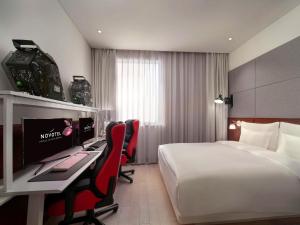 Novotel Shanghai Hongqiao Exhibition في شانغهاي: غرفة في الفندق بها سرير ومكتب وبه جهاز كمبيوتر