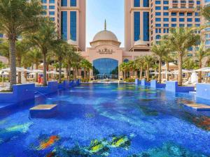 Rixos Marina Abu Dhabi في أبوظبي: مسبح وسط منتجع فيه نخيل