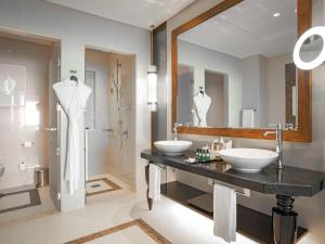 a bathroom with two sinks and a large mirror at Rixos Marina Abu Dhabi in Abu Dhabi