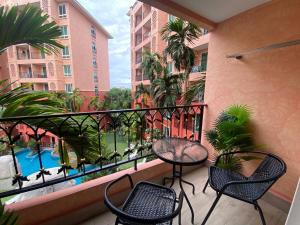 een balkon met een tafel en stoelen en een zwembad bij ΛPΛRTMENTS in Seven Seas condo in Jomtien Beach
