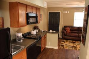 a small kitchen with a stove and a couch at Eagle's Den Suites Big Spring a Travelodge by Wyndham in Big Spring