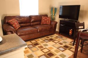 a brown leather couch in a living room with a flat screen tv at Eagle's Den Suites Big Spring a Travelodge by Wyndham in Big Spring