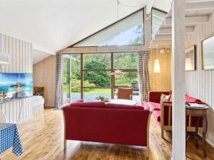 een woonkamer met rode meubels en een groot raam bij Holiday Home Wilgrib - 400m from the sea in Sealand by Interhome in Højby