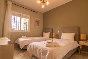 a bedroom with two beds with white sheets and a window at Luxury apartment in Miraflores in La Cala de Mijas