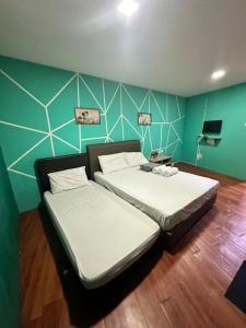 um quarto com 2 camas e uma parede verde em TANGERINE ORIENTAL HOTEL em Kuala Lumpur