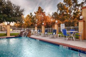 a swimming pool with chairs and a table and a fountain at Days Inn & Suites by Wyndham Sam Houston Tollway in Houston