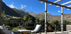 Hotel Central Plaza, Old Stancia Kazbegi في كازباجي: بلكونه فيها طاوله وكراسي وجبال