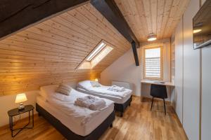 two beds in a room with a wooden ceiling at Wilczy Zew Private Spa & Nature in Borne